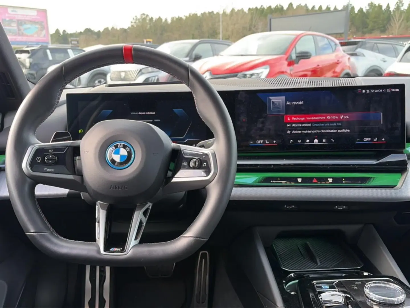 Vue intérieure frontale du tableau de bord et volant noir de la BMW Série 5 i5 M60 avec écran large et insert vert.