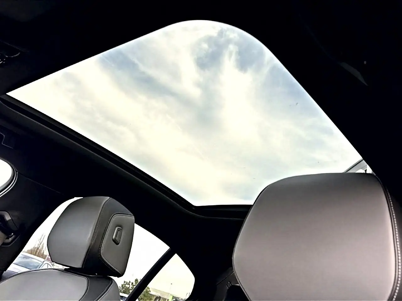 Vue intérieure du toit vitré panoramique et des appuie-têtes en cuir gris de la BMW Série 5 i5 M60 2024.