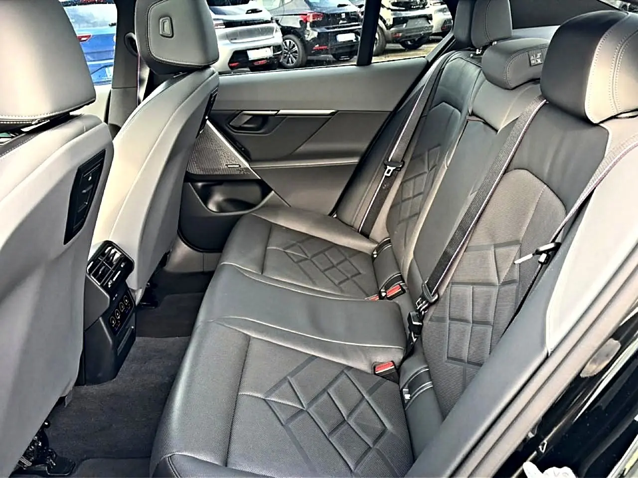 Vue intérieure côté droit des sièges arrière en cuir noir avec surpiqûres et accoudoir central de la BMW Série 5 i5 M60 2024.