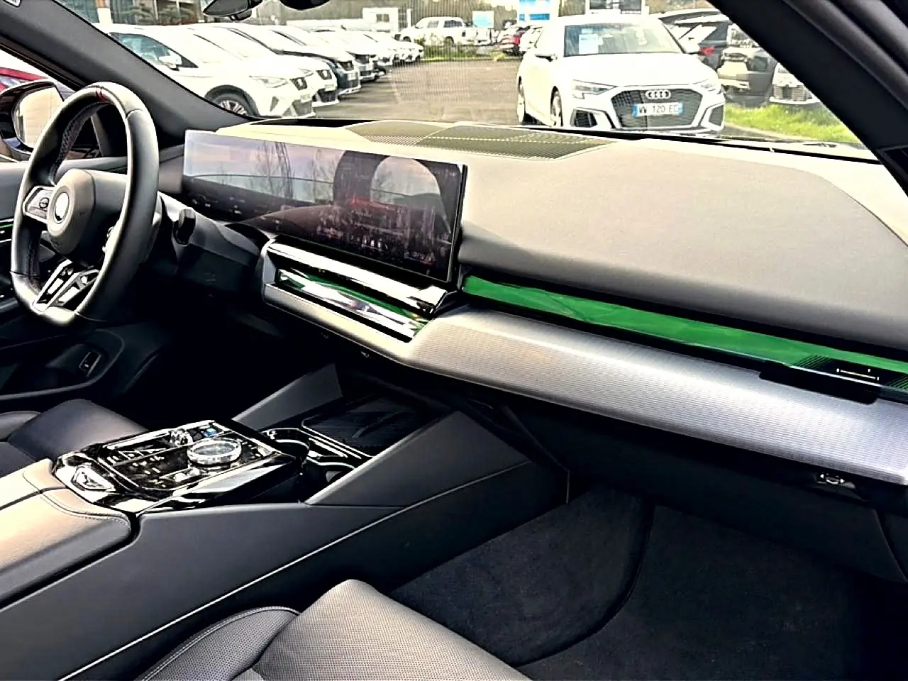 Vue intérieure côté conducteur de la BMW Série 5 i5 M60 2024, tableau de bord moderne avec écran large et finitions noires.