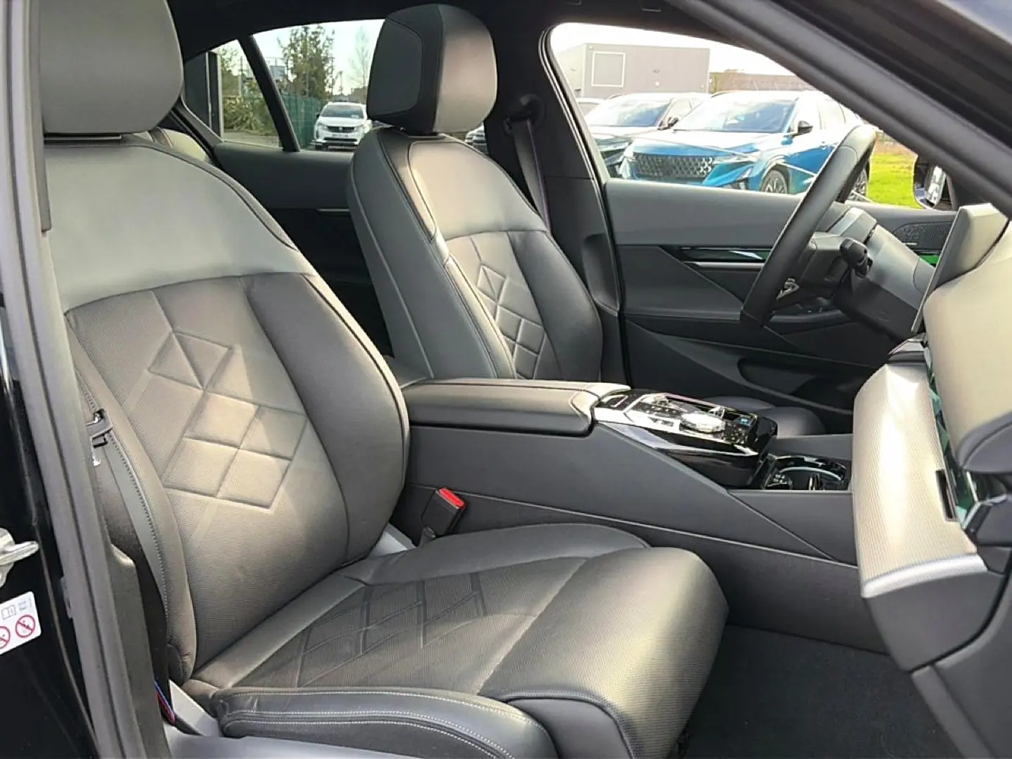 Intérieur avant droit de la BMW Série 5 i5 M60 2024, sièges cuir noirs avec surpiqûres et console centrale élégante.