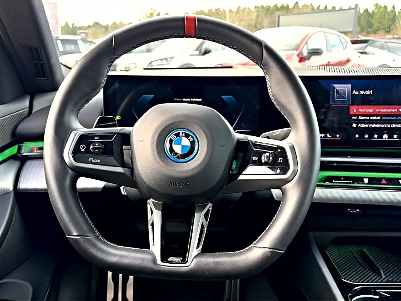 Vue intérieure centrée sur le volant sport noir avec surpiqûre rouge de la BMW Série 5 i5 M60 2024.