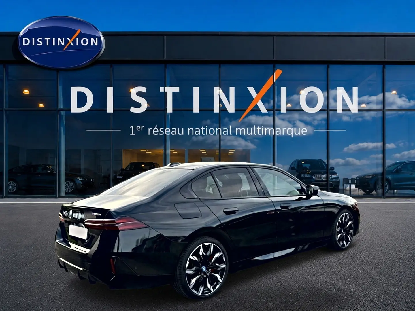 BMW Série 5 i5 M60 noire vue en 3/4 arrière droit, avec jantes alu bicolores et logo M visible sur le coffre.