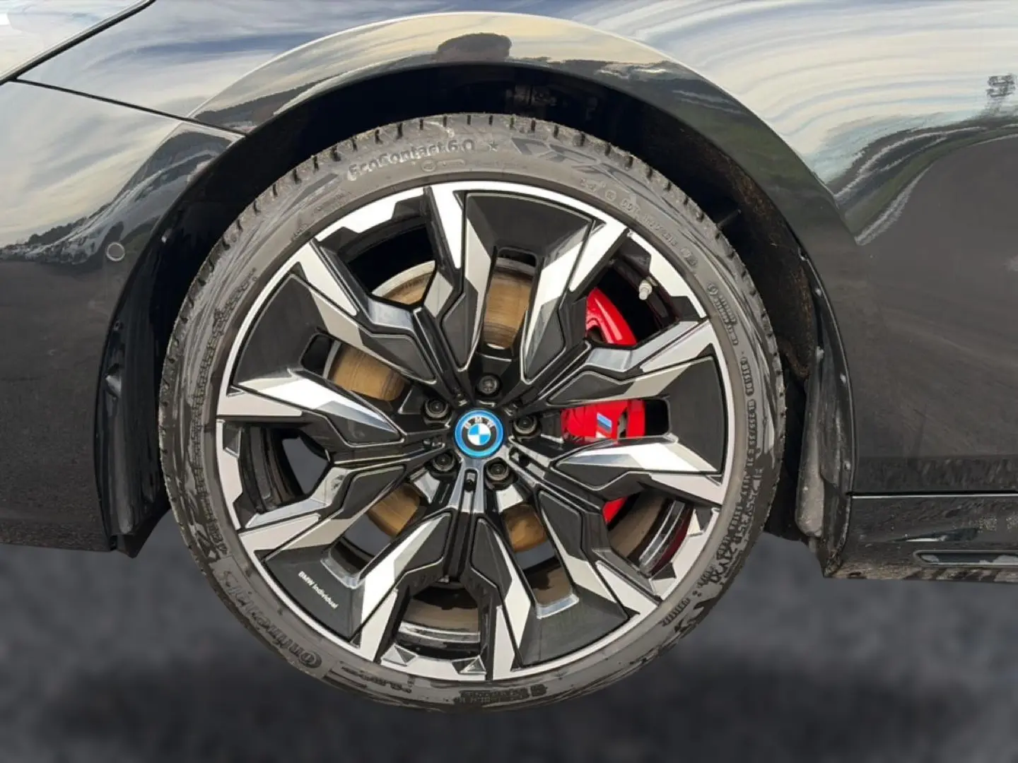 Gros plan sur la jante alu bicolore noire et argentée avec étrier de frein rouge d'une BMW Série 5 i5 M60 noir.
