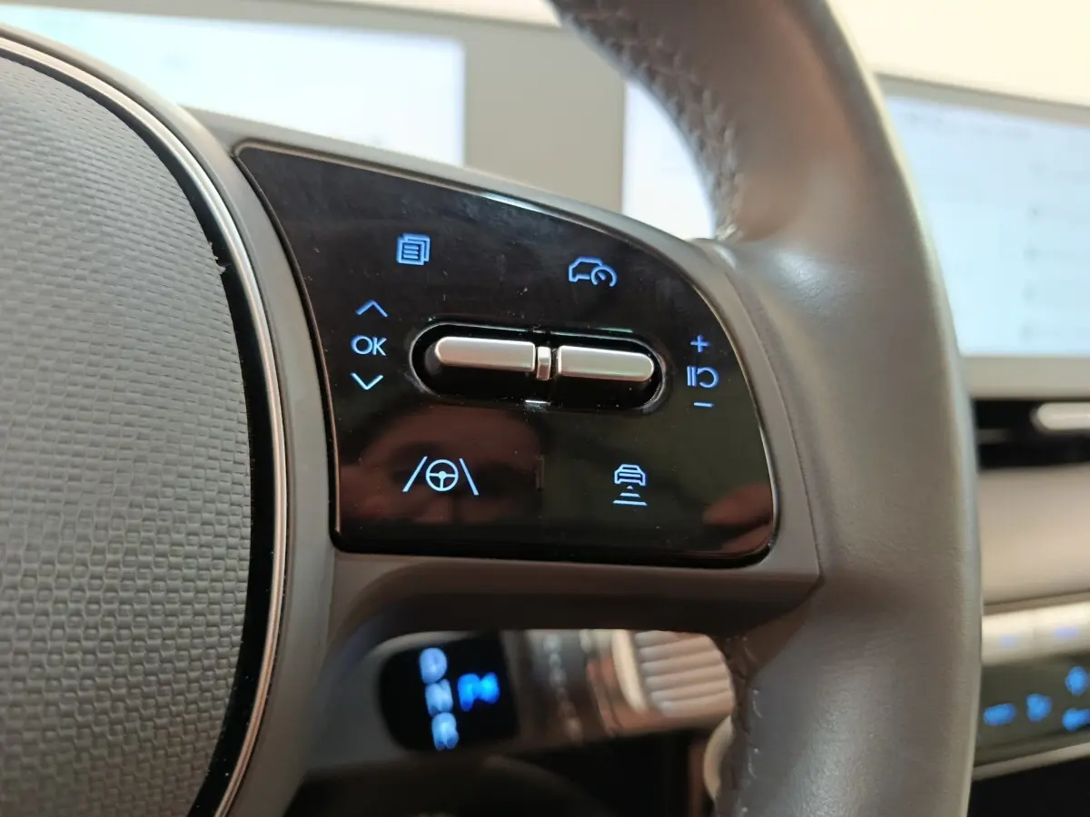 Gros plan sur les commandes au volant cuir beige du Hyundai IONIQ BEV 77KWH AWD Executive 2023.