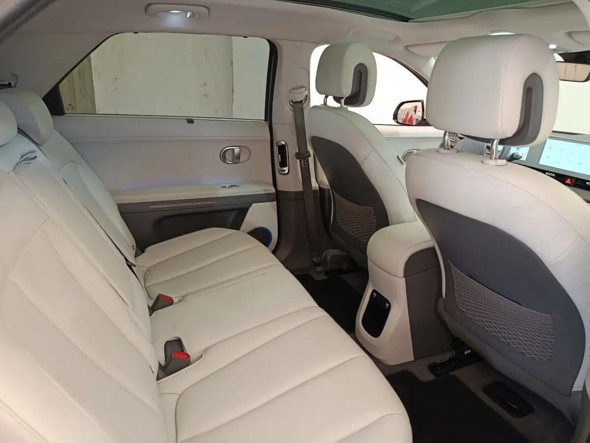 Vue intérieure côté gauche montrant la banquette arrière beige et les dossiers des sièges avant du Hyundai IONIQ BEV 2023.
