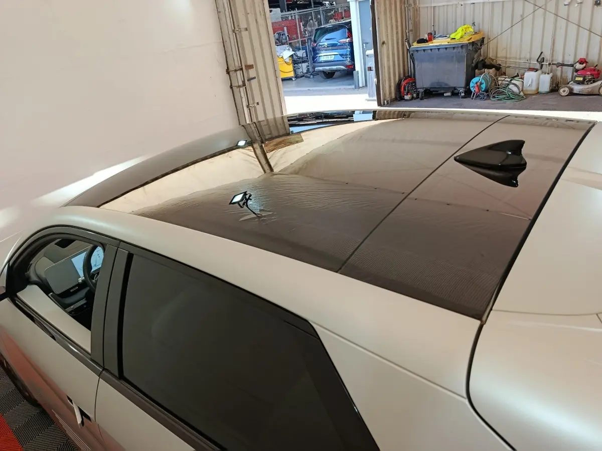 Vue en plongée côté gauche d'une Hyundai IONIQ beige 2023 avec toit panoramique noir et antenne requin.