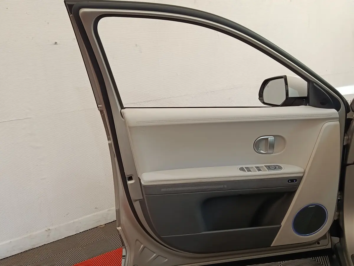 Vue intérieure de la porte avant gauche beige de la Hyundai IONIQ BEV 77KWH AWD Executive 2023 avec haut-parleur Bose.