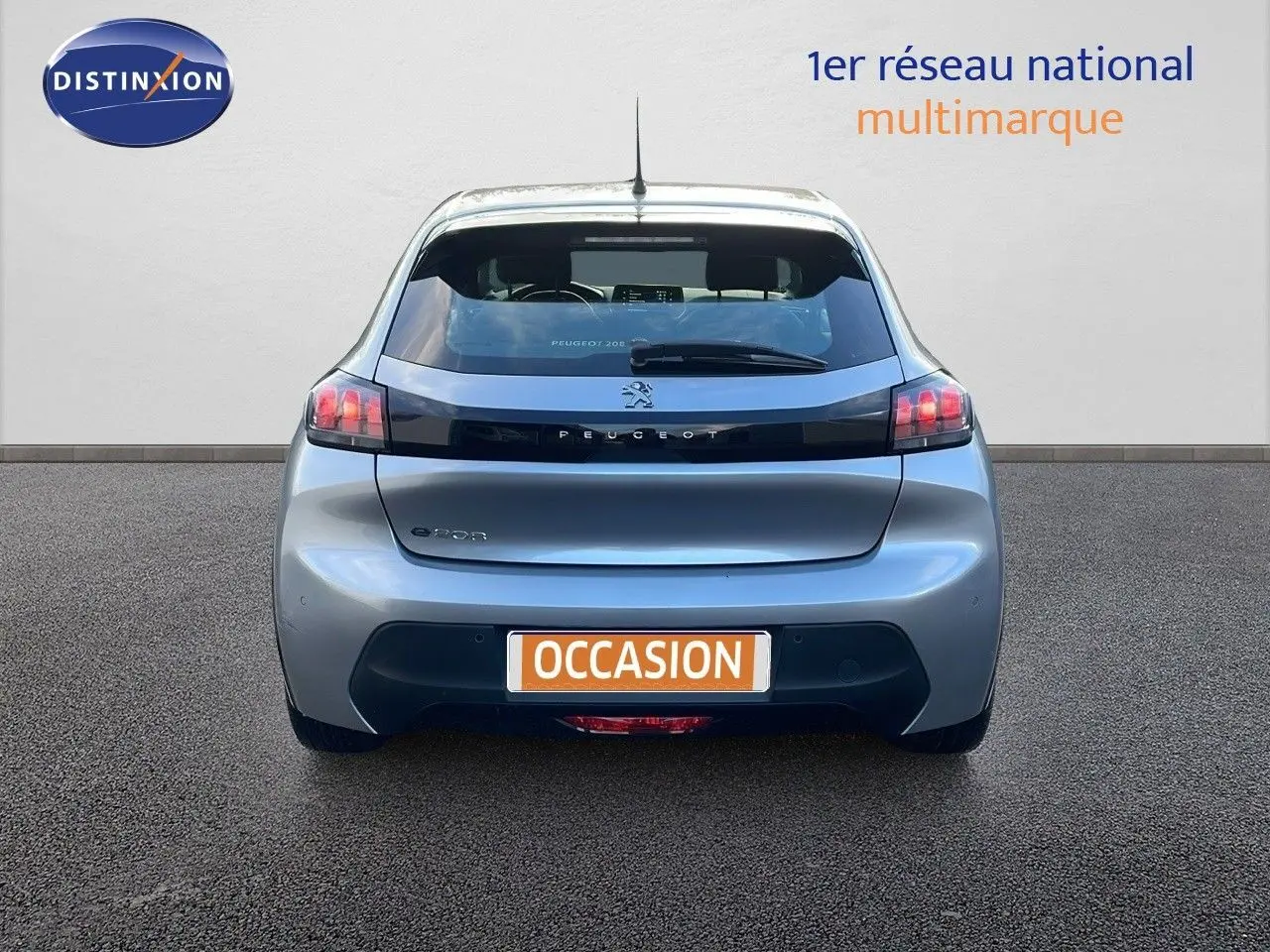Vue arrière d'une Peugeot 208 électrique gris Artense avec feux arrière distinctifs et logo Peugeot visible.