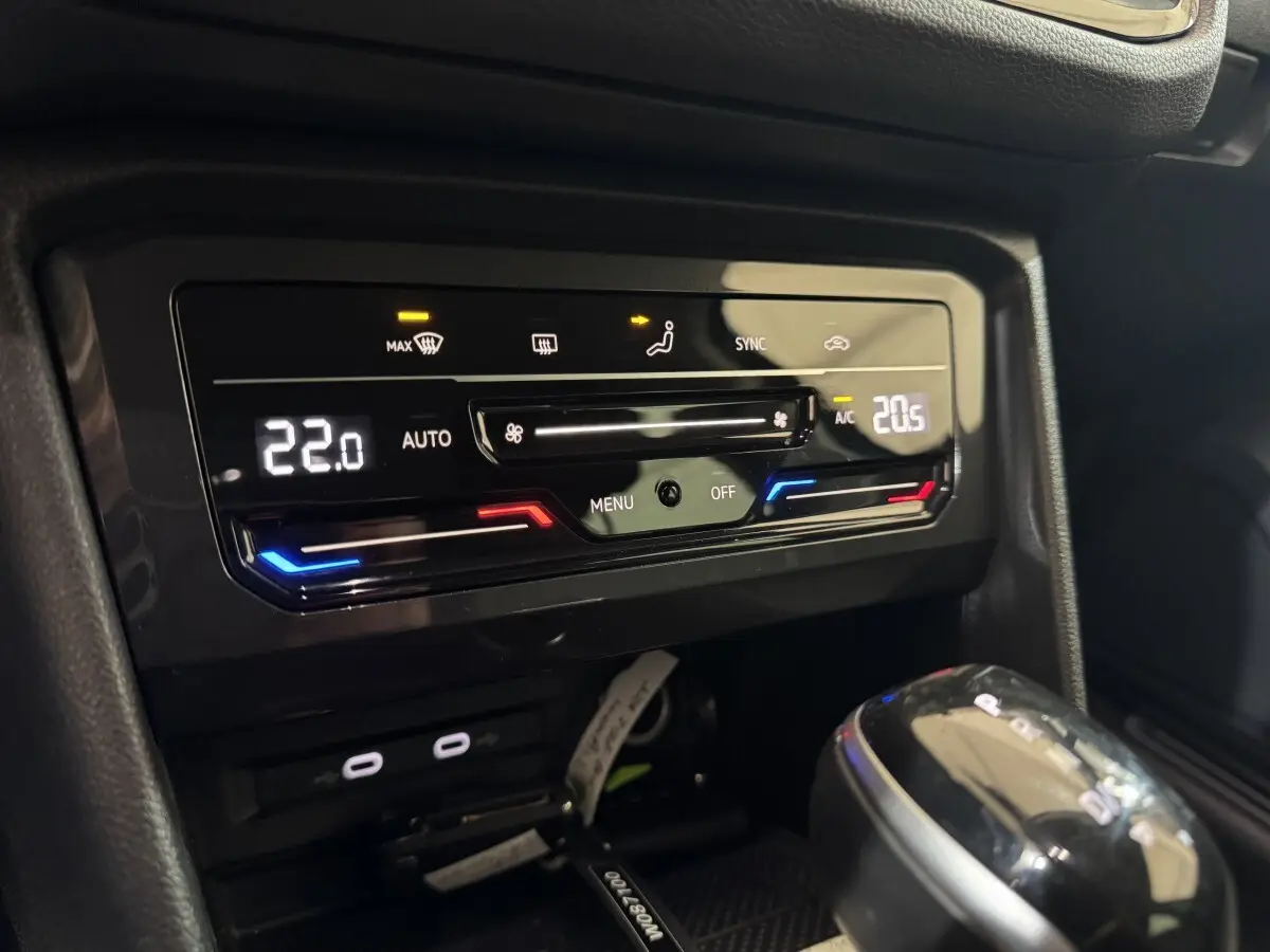 Vue rapprochée de la console centrale du Volkswagen Tiguan bleu 2021, montrant la climatisation digitale et le levier de vitesse.