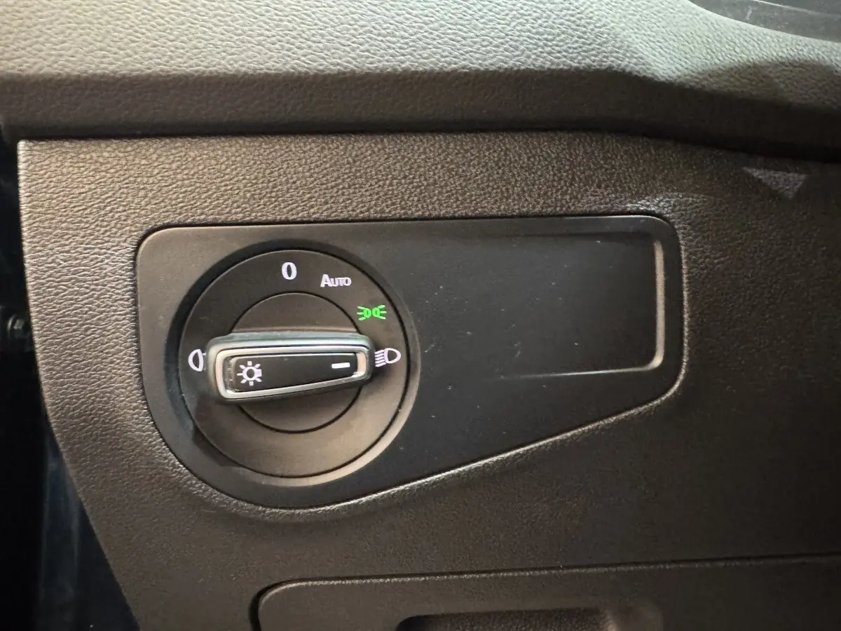 Gros plan sur la molette de commande des phares du Volkswagen Tiguan 1.5 TSI 150 DSG7 Life Business, intérieur noir.