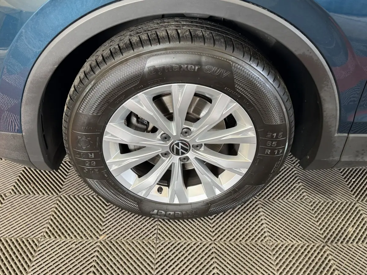 Gros plan sur la roue avant droite d’un Volkswagen Tiguan bleu avec jante alliage et pneu Dynaxer SUV.