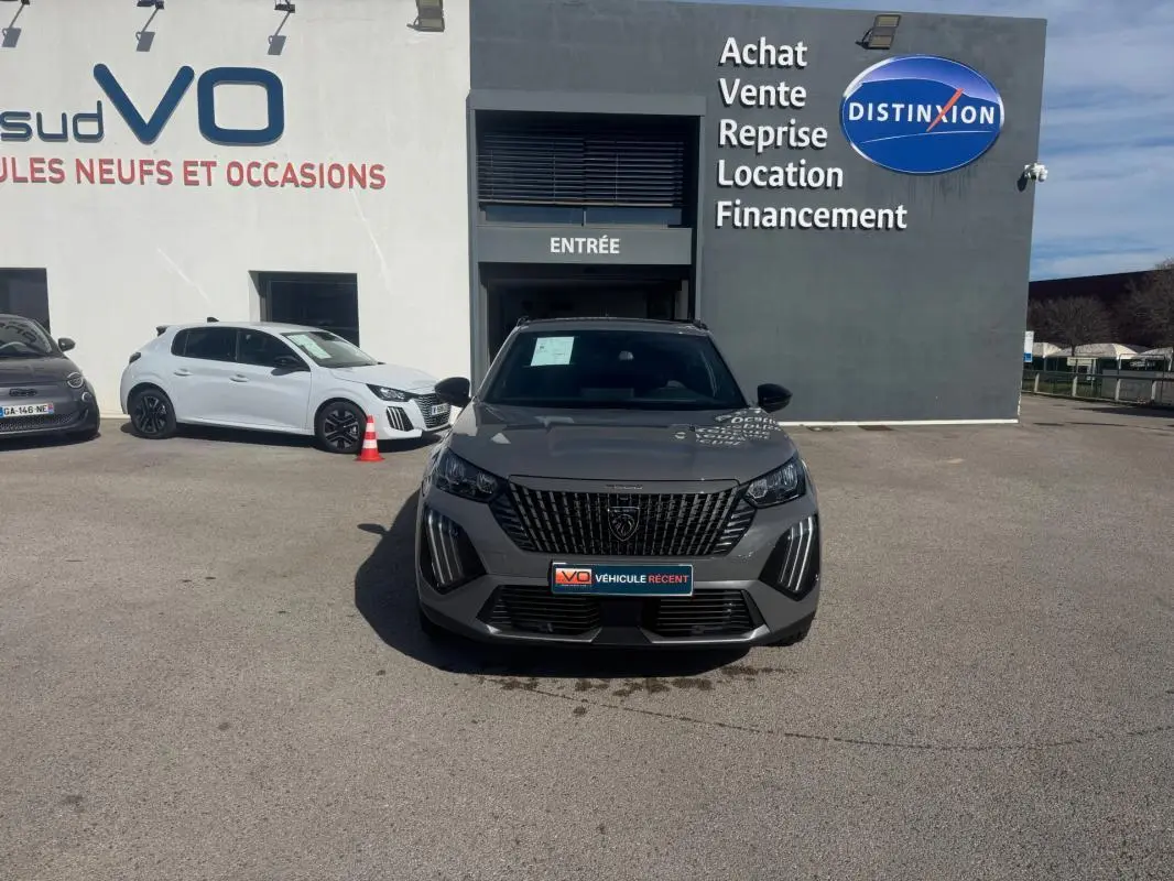 Peugeot 2008 Hybrid 145 gris vue de face, calandre verticale noire et feux LED en forme de griffes.