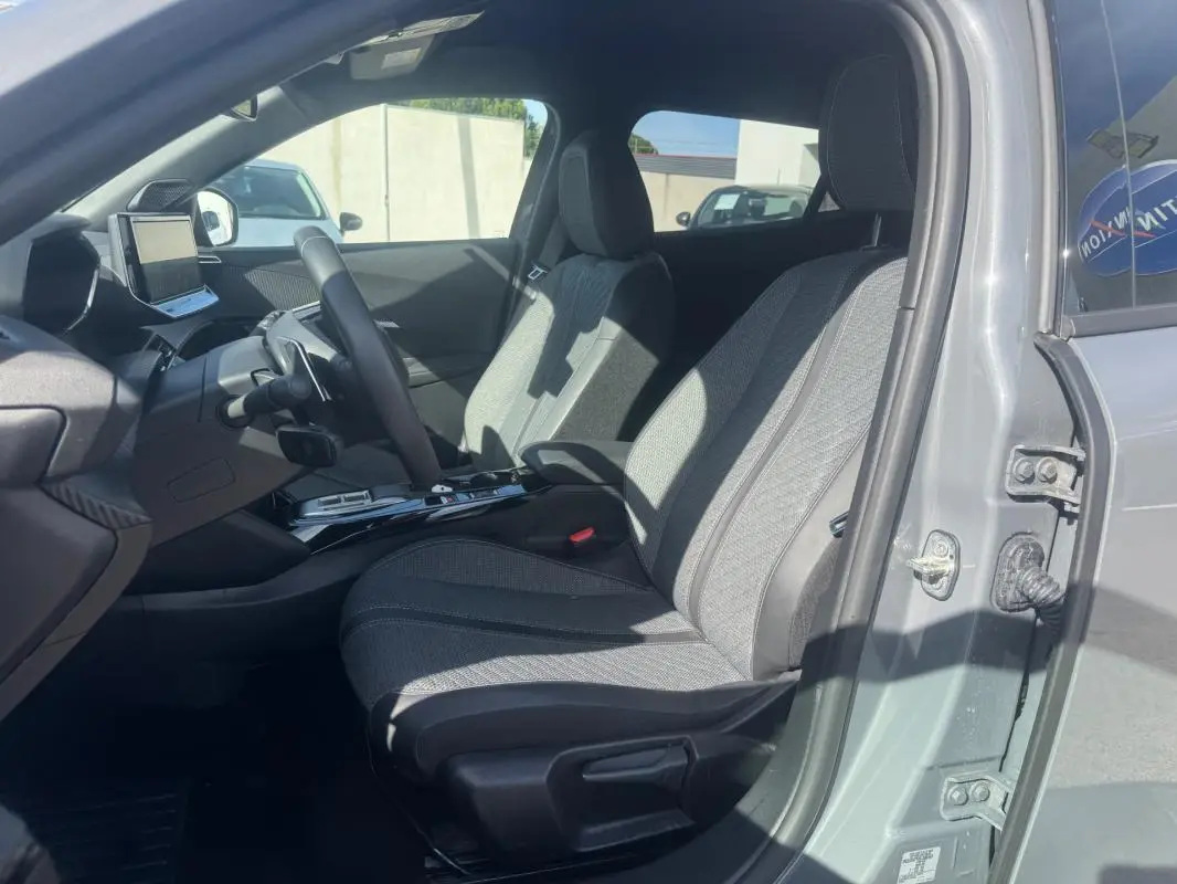 Intérieur de la Peugeot 2008 Hybrid gris, vue côté conducteur ouverte, sièges tissu gris et tableau de bord moderne.