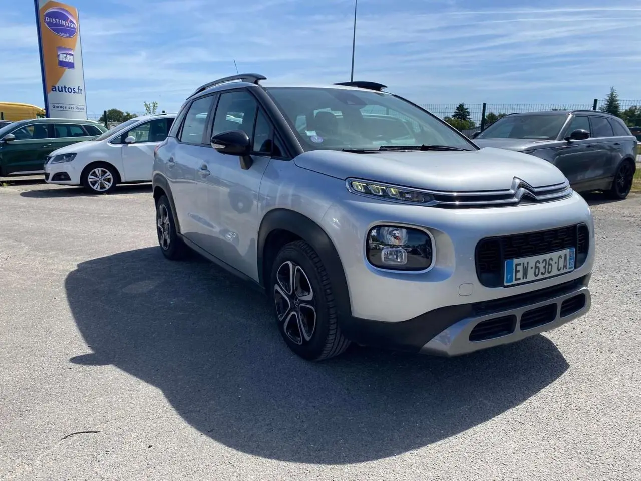 Vue 3/4 avant d'un Citroën C3 Aircross gris Artense avec toit noir et jantes distinctives, stationné en extérieur.