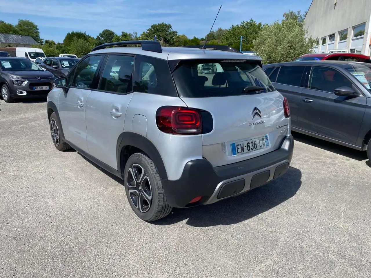 Vue 3/4 arrière droite d'un Citroën C3 Aircross gris Artense avec toit noir et jantes distinctives, stationné en extérieur.