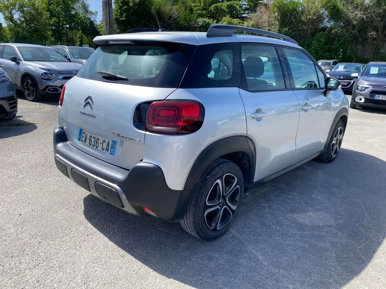Vue 3/4 arrière droite d'un Citroën C3 Aircross gris Artense avec toit noir et jantes distinctives, stationné en extérieur.