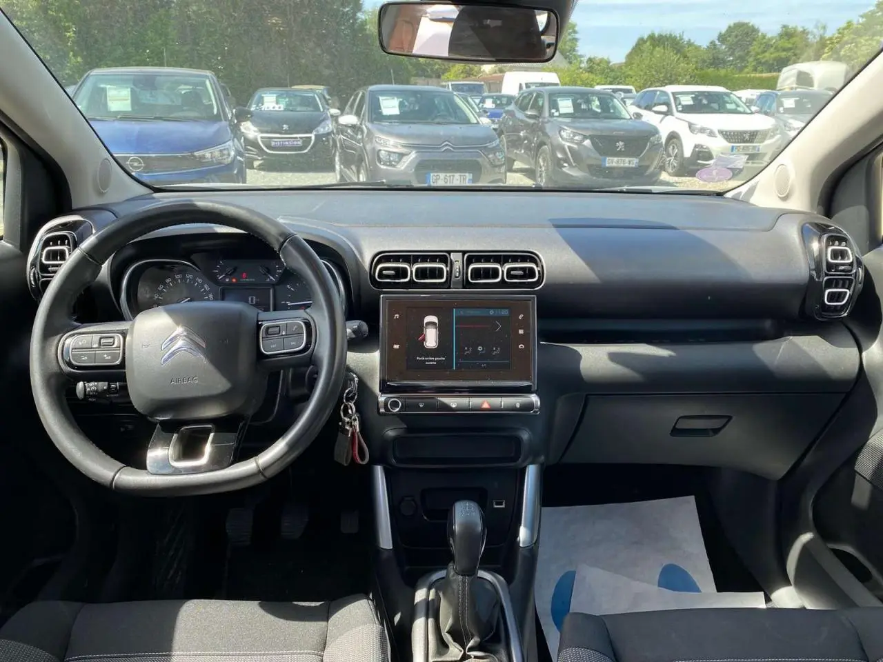 Vue intérieure frontale du tableau de bord du Citroën C3 Aircross gris Artense, avec volant multifonction et écran tactile central.
