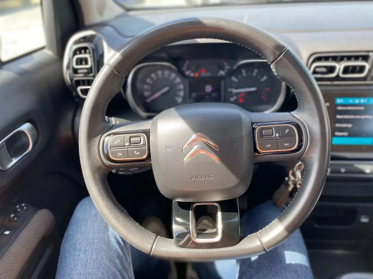 Vue rapprochée du volant noir du Citroën C3 Aircross 2018, avec commandes intégrées et tableau de bord en arrière-plan.