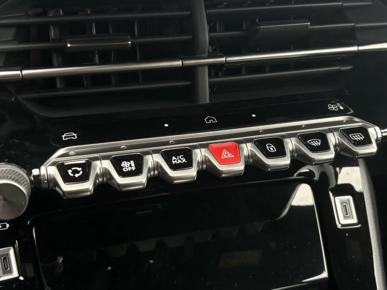 Vue rapprochée de la console centrale noire de la Peugeot 208 Hybrid 110 e-DSC6 GT avec boutons de commande argentés et rouge d’alerte.