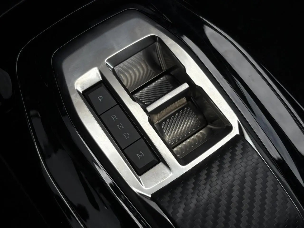 Gros plan sur le sélecteur de vitesses automatique en aluminium et noir dans la console centrale d'une Peugeot 208 Hybrid 110 e-DSC6 GT.
