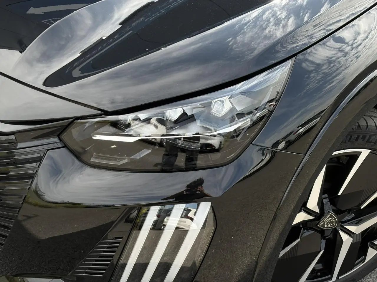 Gros plan sur l'avant droit noir Perla du Peugeot 208 Hybrid 110 e-DSC6 GT avec phares LED et jante diamantée 17''.