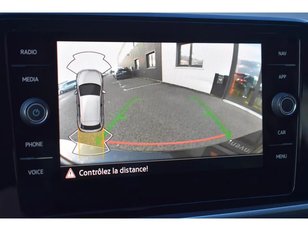 Affichage de la caméra de recul du Volkswagen T-Roc 2025 avec guidage de trajectoire et alerte de distance sur écran tactile.