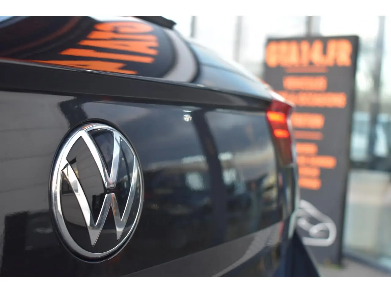 Gros plan sur l'arrière droit d'un Volkswagen T-Roc 2025 noir métallisé avec logo VW et feu arrière LED rouge.