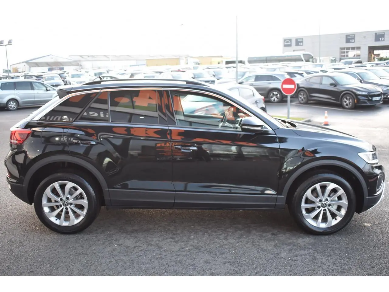 Vue latérale droite du Volkswagen T-Roc 2025 noir métallisé avec jantes alliage 17 pouces sur parking extérieur.
