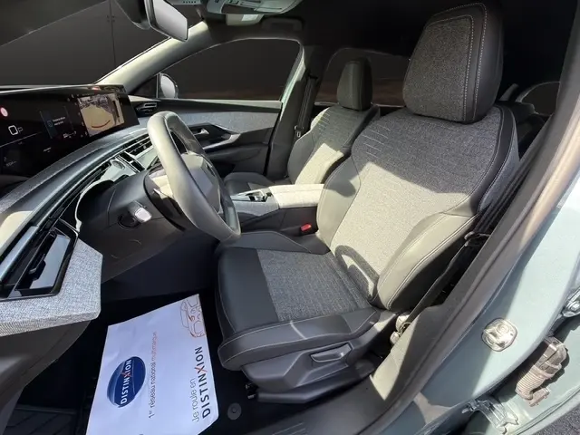 Vue intérieure côté conducteur du Peugeot 5008 bleu 2025, mettant en valeur les sièges tissu et cuir, le volant multifonctions et l'écran tactile.