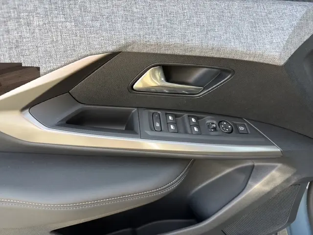 Vue rapprochée de la porte côté conducteur du Peugeot 5008 bleu 2025, avec commandes électriques et poignée argentée.