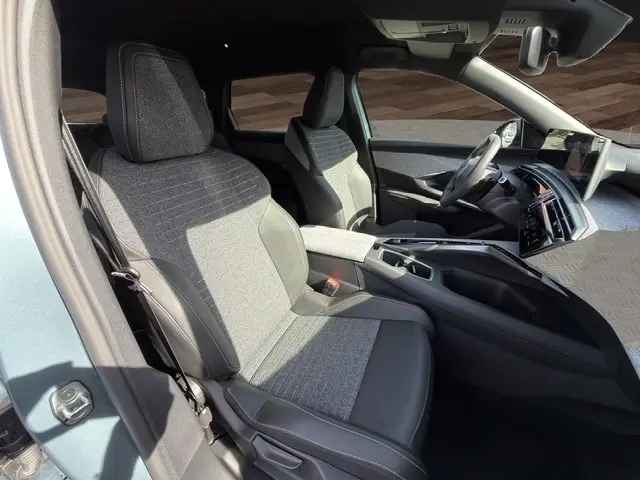 Vue intérieure côté conducteur du Peugeot 5008 bleu 2025, sièges tissu et cuir, tableau de bord moderne avec écran tactile.