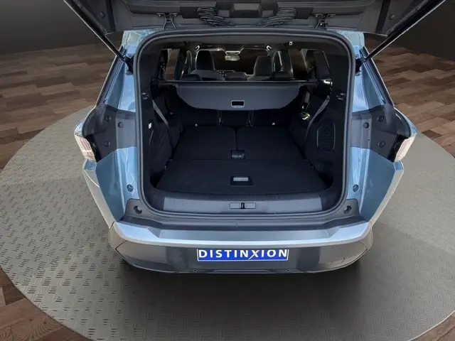 Coffre ouvert vu de l'arrière d'un Peugeot 5008 bleu 2025, montrant les sièges rabattus et l'espace intérieur spacieux.