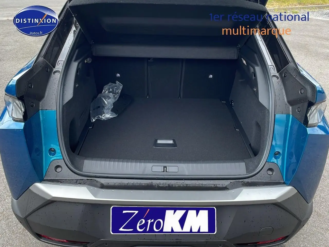 Coffre ouvert en vue arrière d'un Peugeot 3008 Hybrid 145 GT e-DS6 bleu obsession avec hayon motorisé visible.