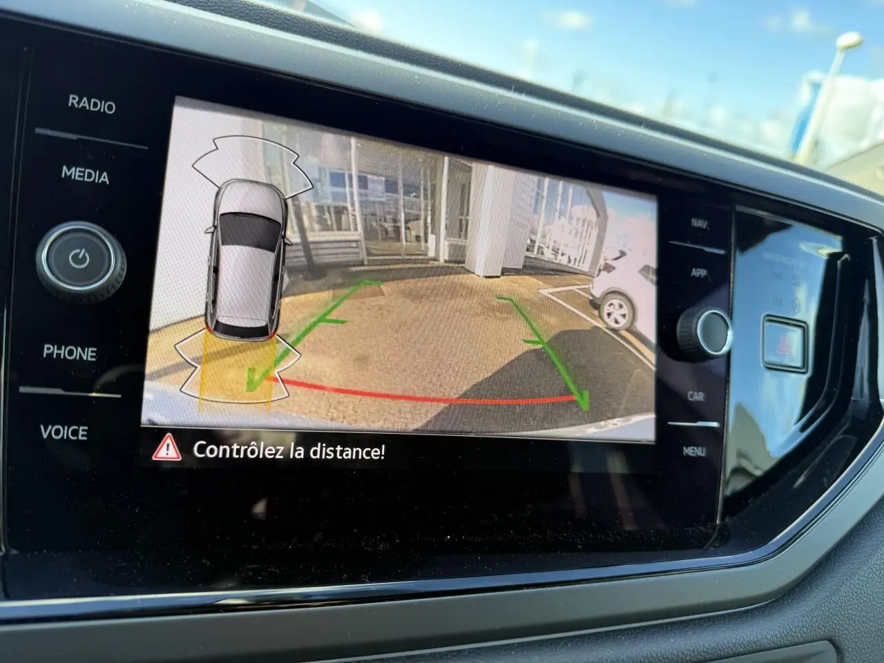 Écran de la caméra de recul affichant l’aide au stationnement d’une Volkswagen Polo blanche pure 2025.