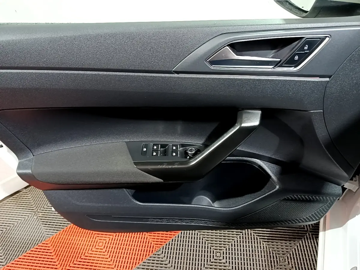 Vue intérieure du panneau de porte avant gauche du Volkswagen Taigo blanc, avec commandes de vitres et verrouillage.