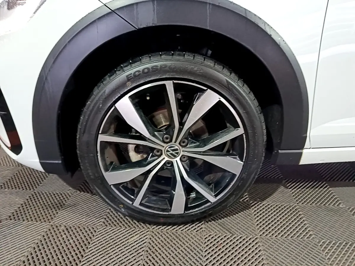 Gros plan sur la roue avant droite du Volkswagen Taigo blanc, mettant en valeur la jante alliage R-Line bicolore.