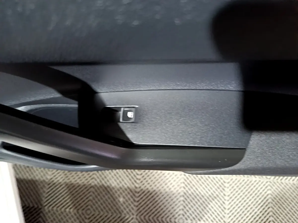 Bouton de verrouillage des portes sur la garniture intérieure noire d'une Volkswagen Taigo blanche, vue en gros plan.