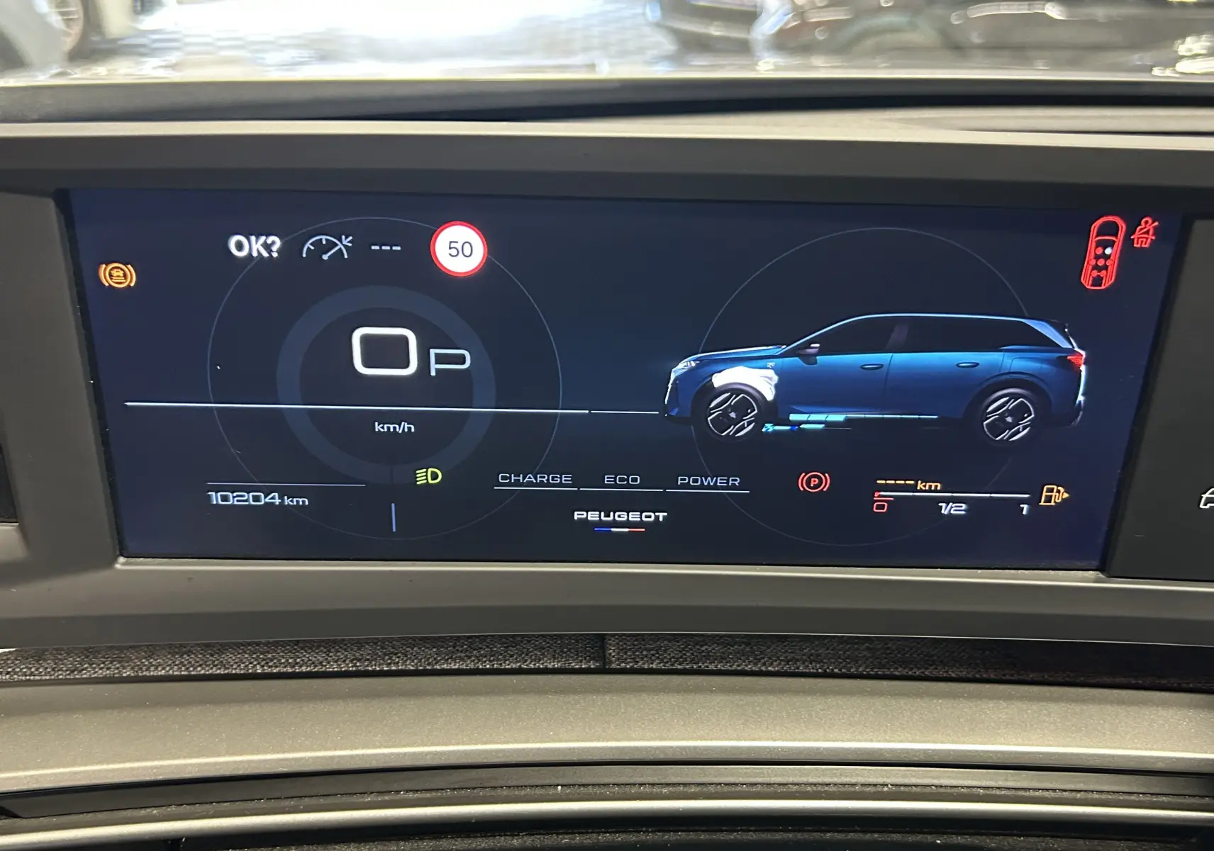 Affichage numérique du tableau de bord du Peugeot 5008 hybride 2025, avec vue latérale bleue du véhicule et indicateurs de vitesse et énergie.