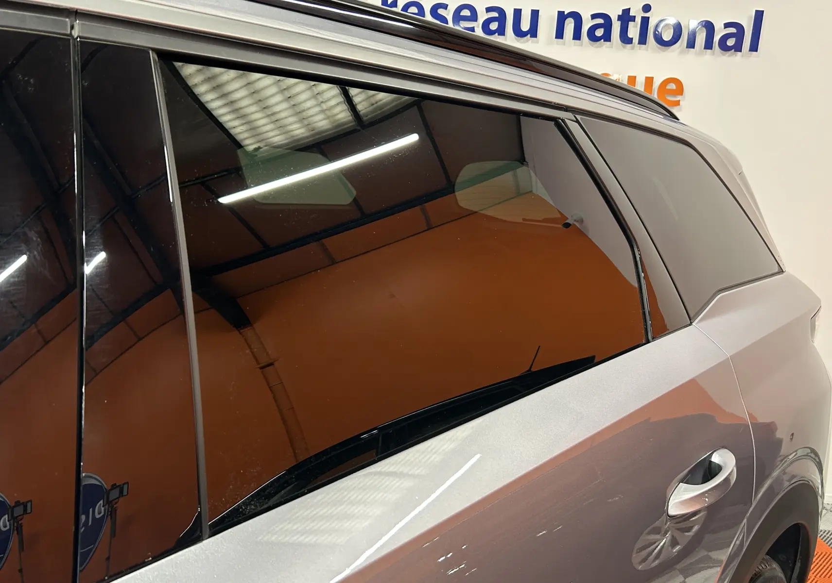 Vue latérale droite sur la porte arrière d’un Peugeot 5008 gris Artense avec vitres teintées en intérieur showroom.