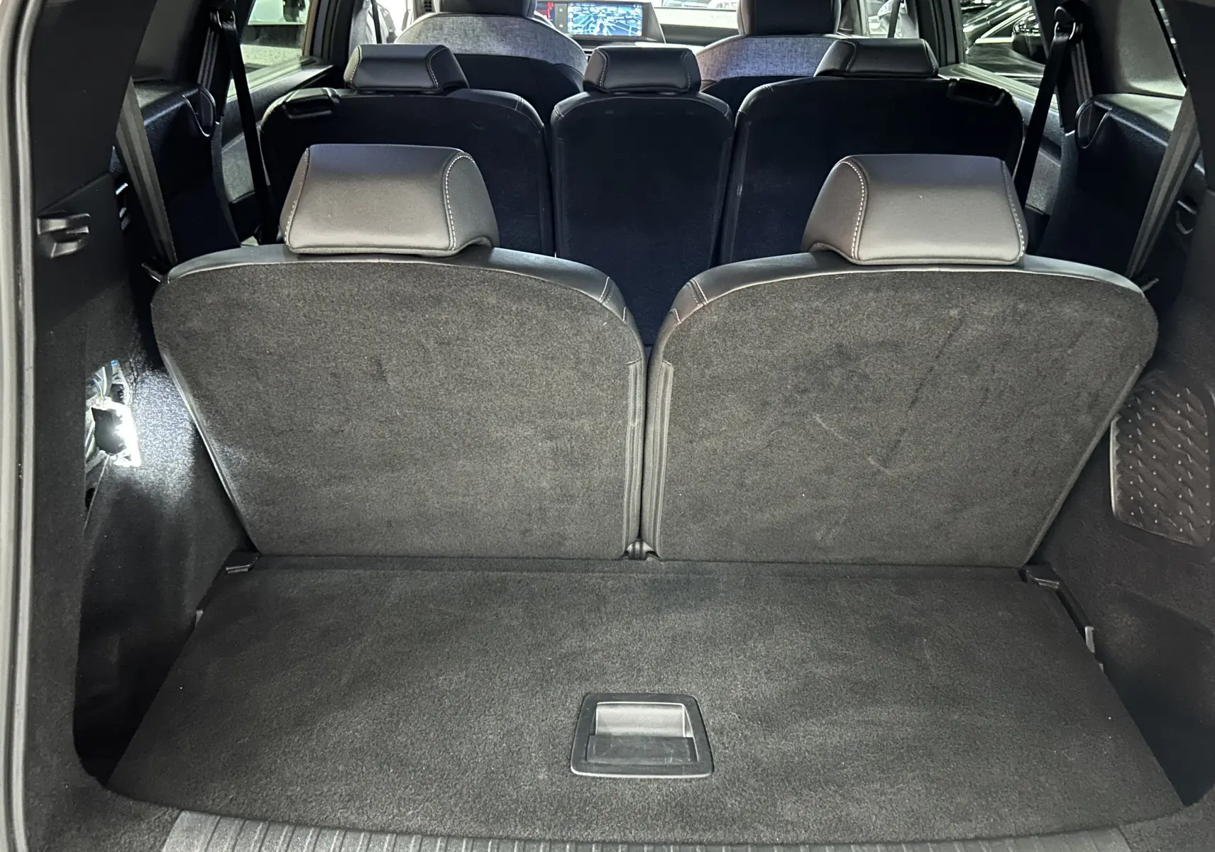 Vue intérieure arrière du coffre du Peugeot 5008 gris Artense avec sièges rabattus et banquette 3e rangée visible.