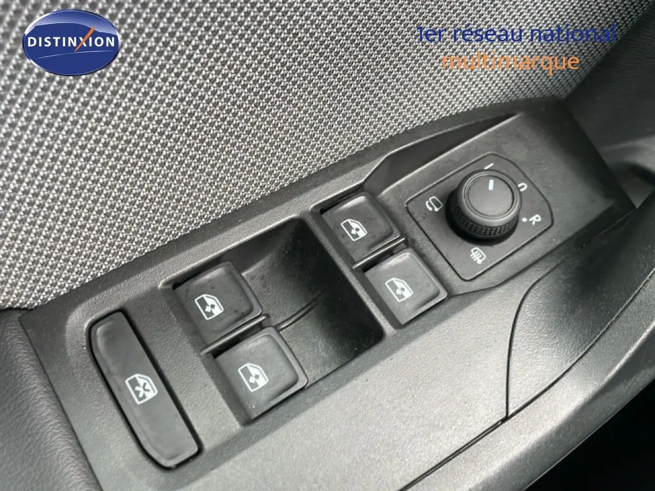 Gros plan sur les commandes des vitres et rétroviseurs côté conducteur d'une SEAT Leon bleu Fjord 2025.