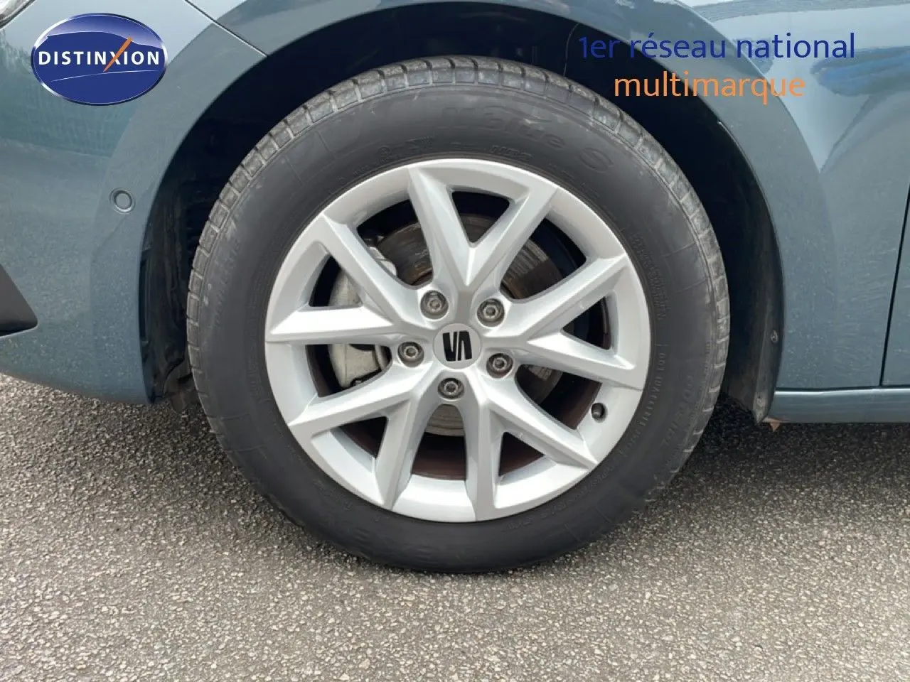 Gros plan sur la roue avant gauche d'une SEAT LEON 2.0 TDI 115CH STYLE XL bleu Fjord avec jante alliage argentée.