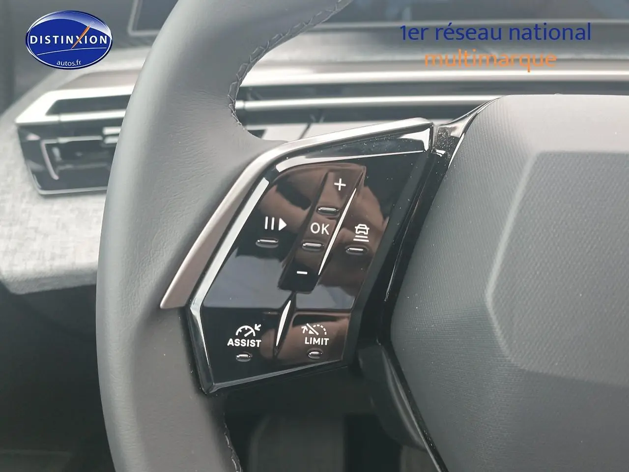 Gros plan sur les commandes au volant cuir du Peugeot 5008 gris Artense, avec tableau de bord en arrière-plan.