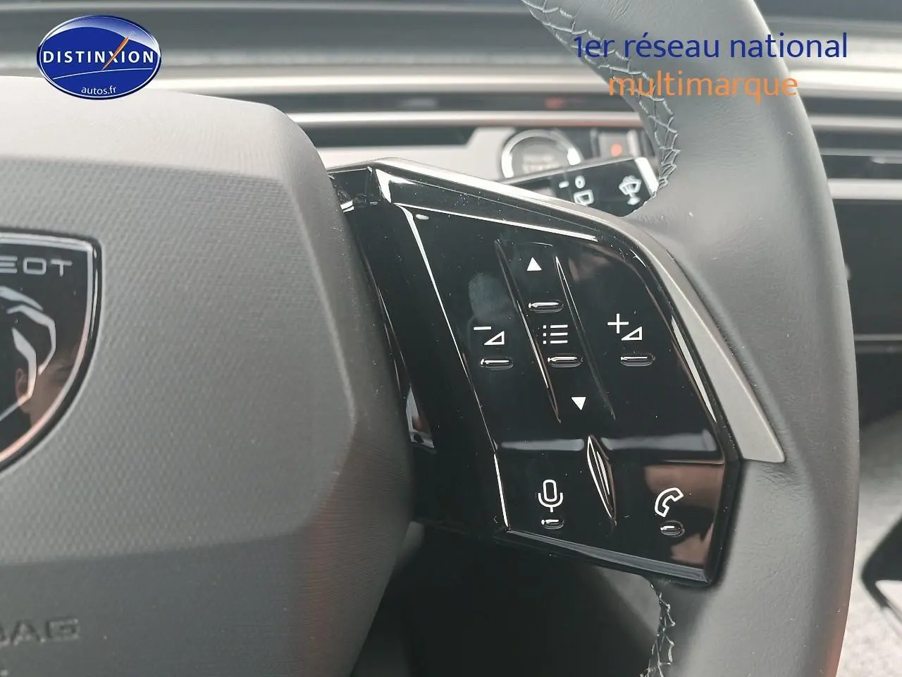 Gros plan sur les commandes vocales et audio au volant cuir du Peugeot 5008 Hybrid 145 gris Artense, côté gauche.