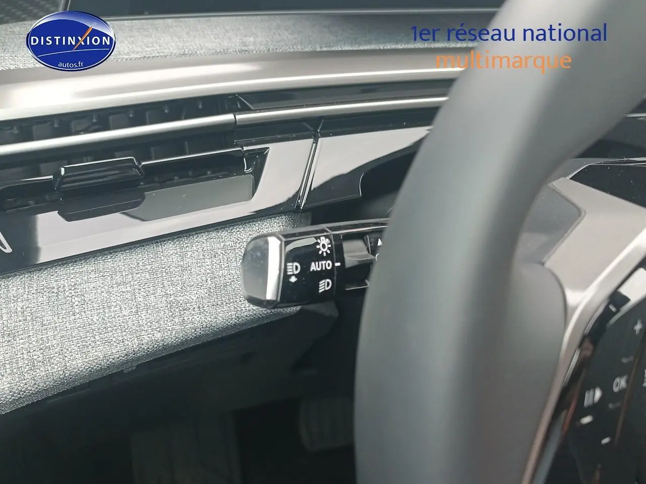 Détail du commodo d’éclairage à gauche du volant dans l’habitacle gris clair du Peugeot 5008 Hybrid 145 allure 2025.