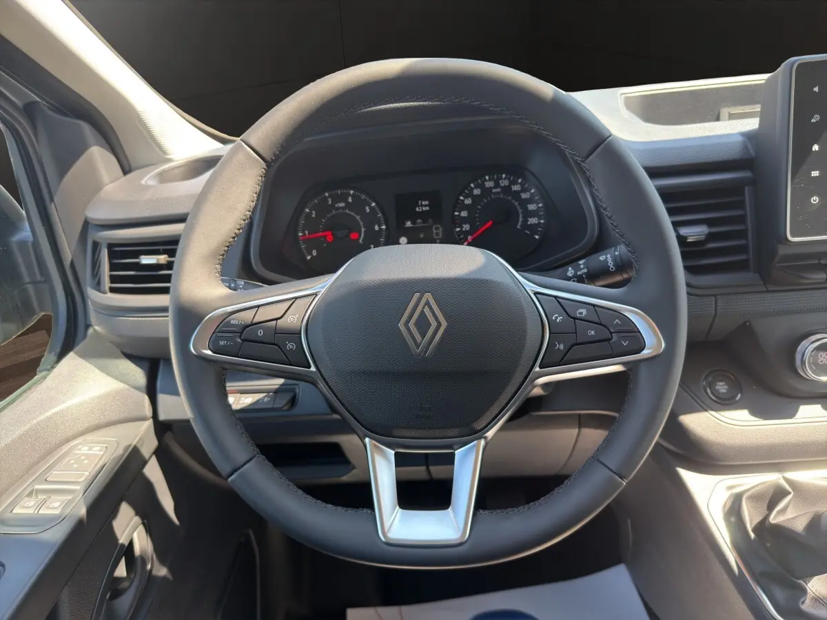 Vue intérieure centrée sur le volant multifonctions noir du Renault Trafic Fourgon avec tableau de bord et commandes visibles.