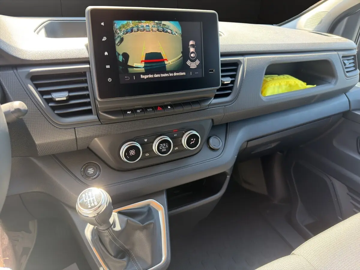 Vue intérieure côté passager du tableau de bord gris foncé du Renault Trafic Fourgon avec écran tactile et levier de vitesse manuel.