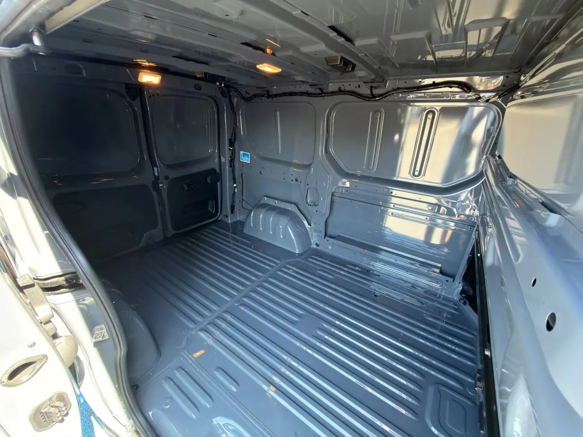 Vue intérieure arrière du fourgon Renault Trafic gris foncé, montrant l'espace de chargement vide et la cloison pleine.
