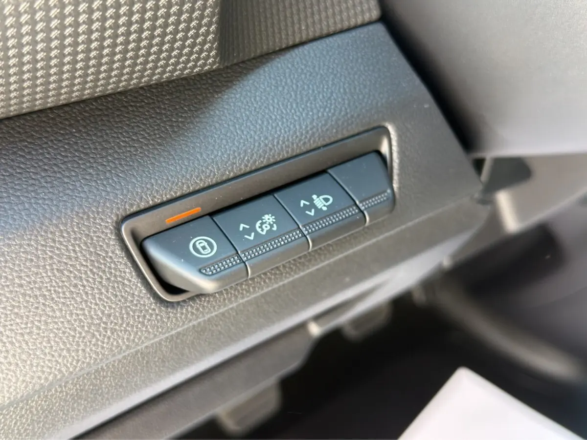 Gros plan sur les commandes de réglage des phares et verrouillage, tableau de bord noir du Renault Trafic gris foncé.